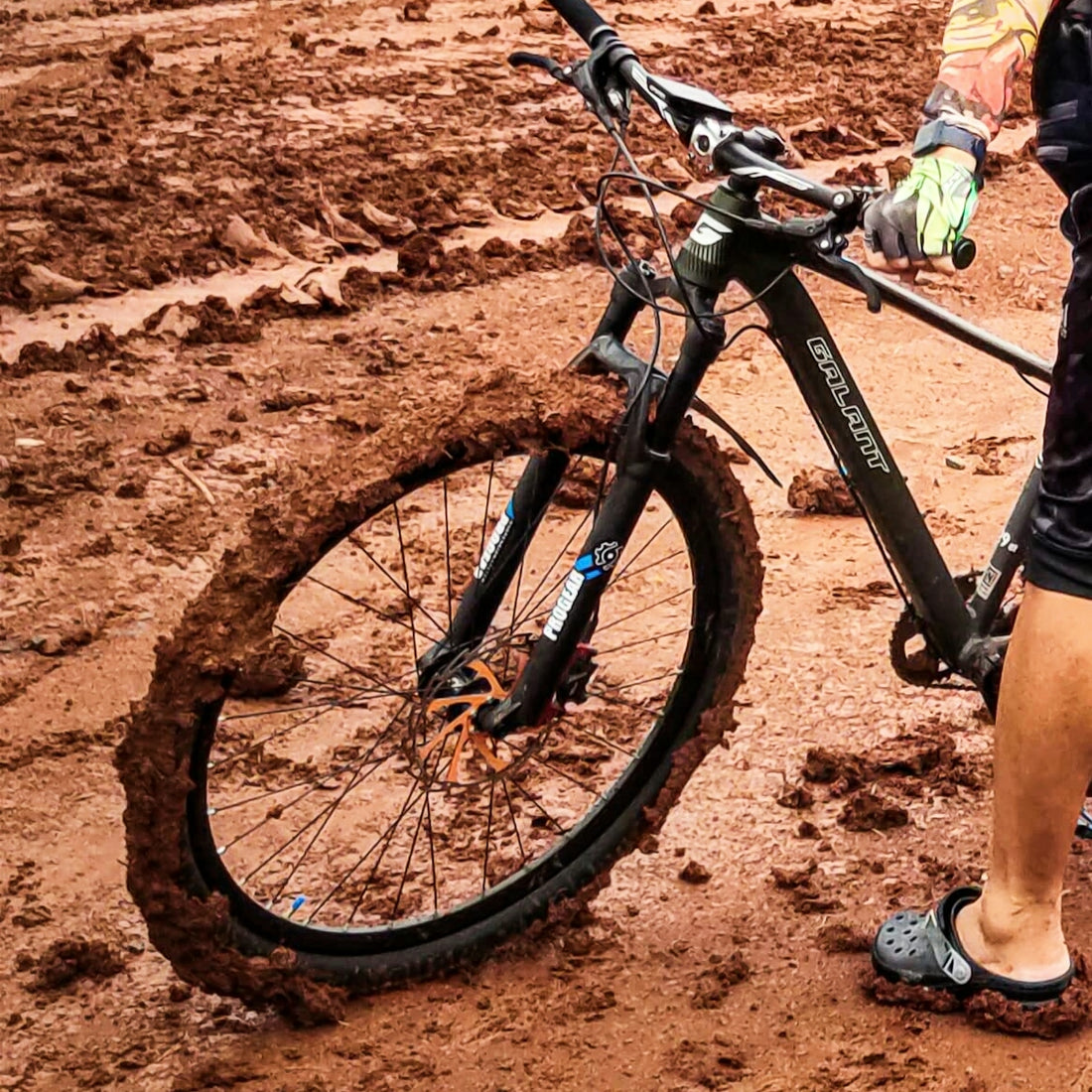 A man standing next to a bike in the mud
