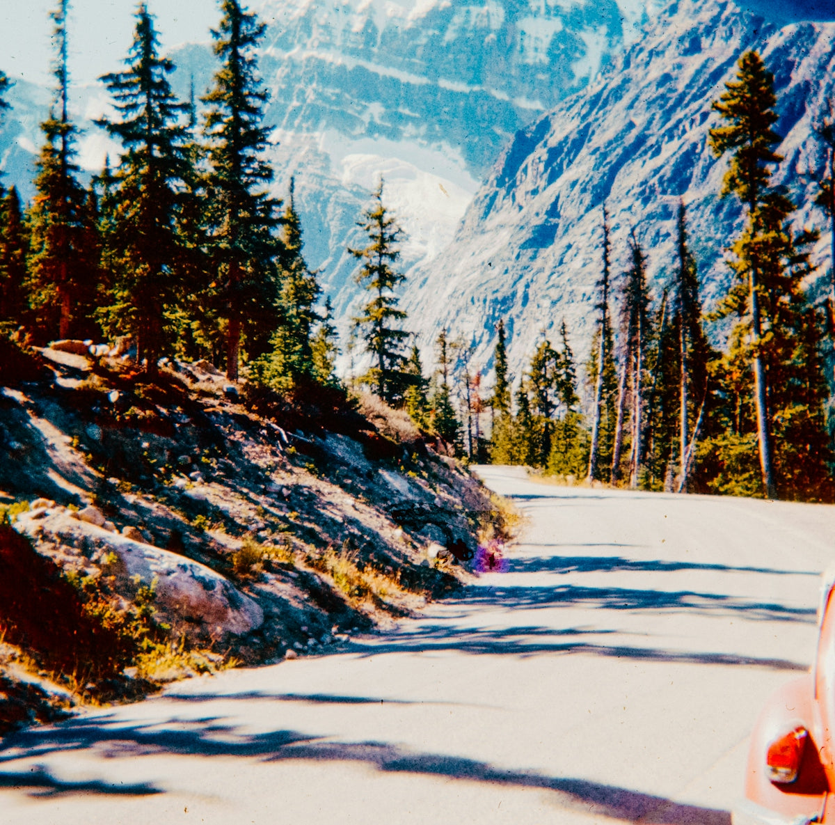 A car driving down a road next to a mountain
