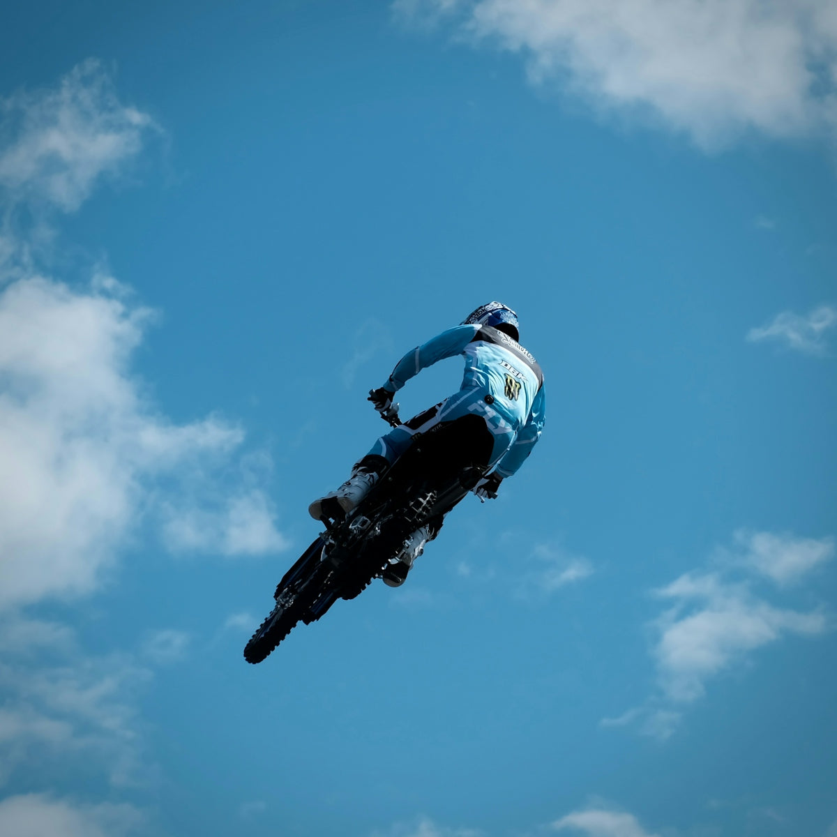 Motocross rider in mid-air against a blue sky.
