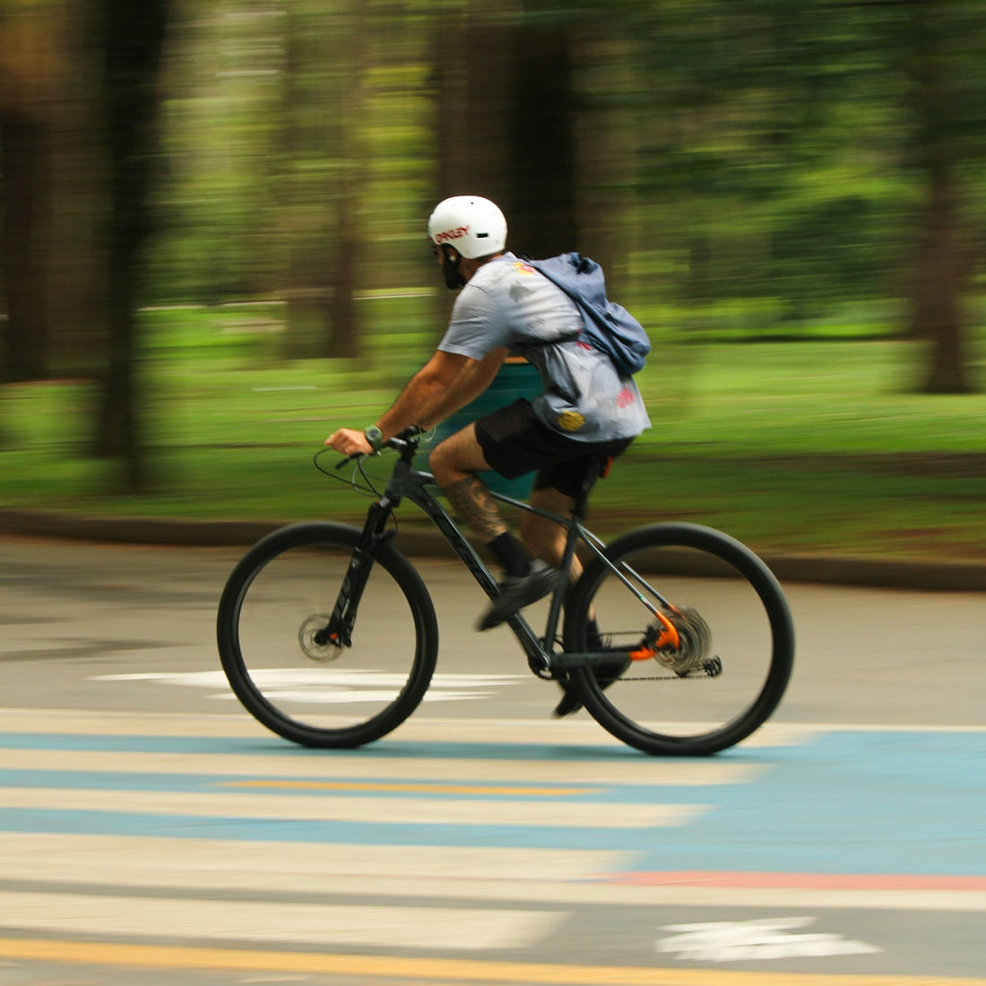 Man riding a bicycle on a road with trees