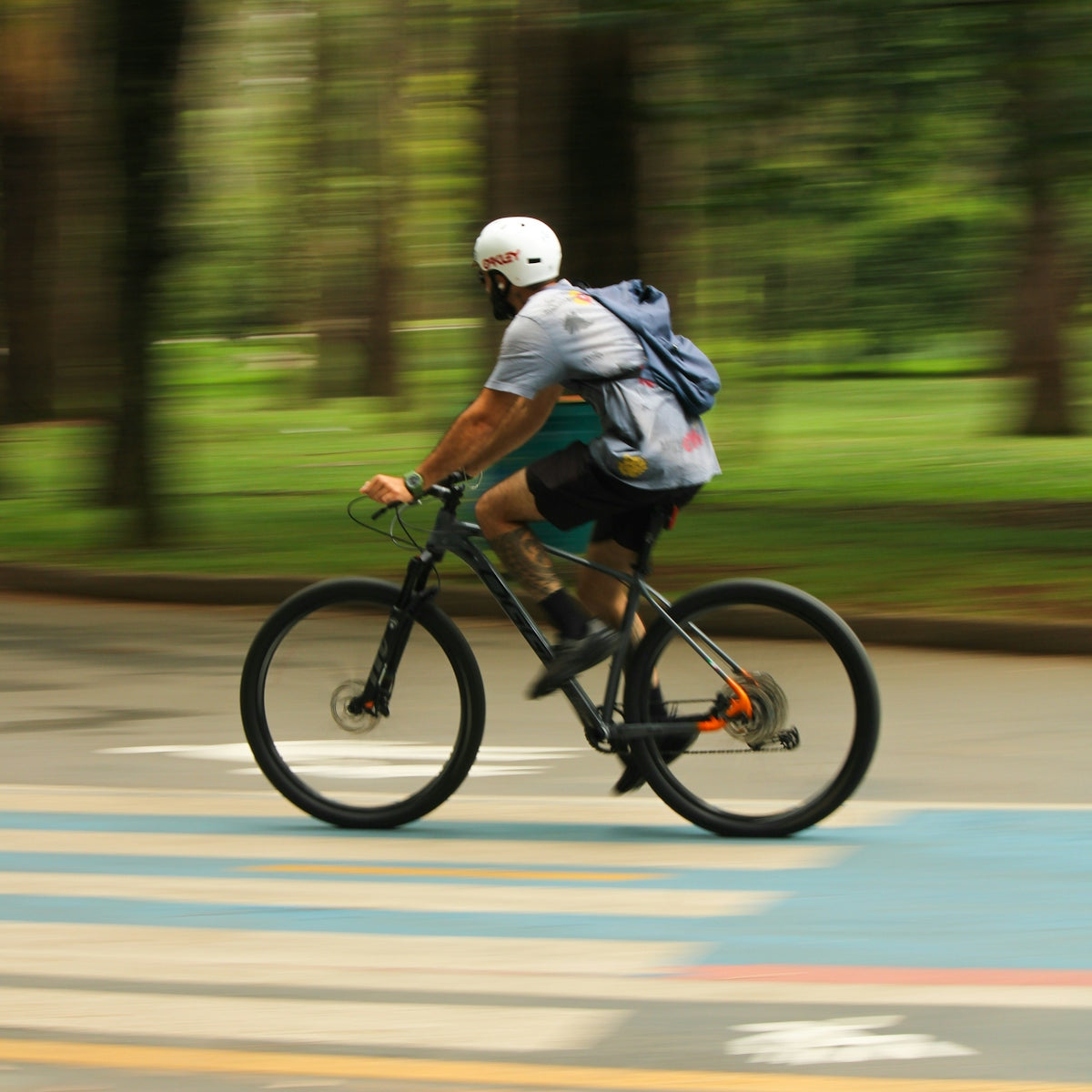 Man riding a bicycle on a road with trees