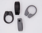 Four clamp-style rings—two black, two gray—are shown on a white background. These interchangeable spare clamps for MTB AirGrips bar clamps each have a small emblem and tightening hole.